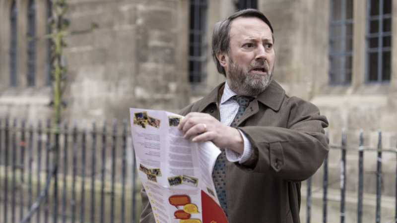   John ‚Ludwig‘ Taylor (David Mitchell) zápasí s letákom o prechádzke po Cambridge v meste Ludwig