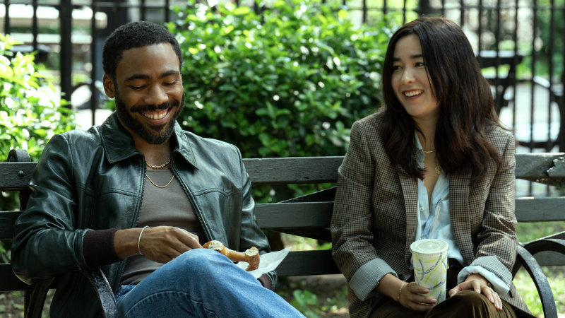   John (Donald Glover) a Jane (Maya Erskine) spolu sedia na lavičke v parku a usmievajú sa v epizóde Mr. & Mrs. Smith 1