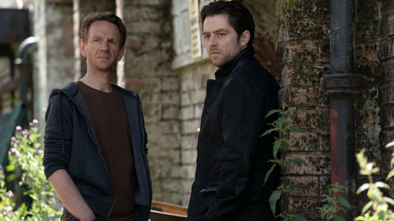   Brian Ferguson ako Michael Rebus a Richard Rankin ako John Rebus stoja pri stene v Rebuse.