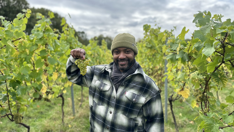   JB Gill se encuentra en un viñedo con uvas en Winter on the Farm.