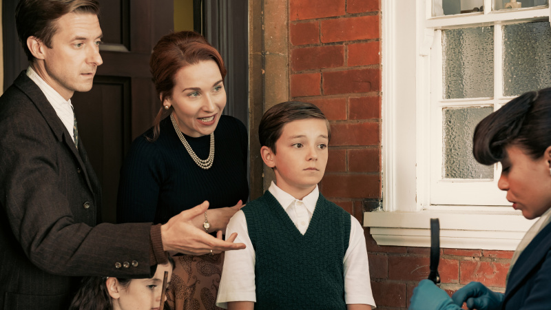   Ernest (Arthur Darvill) Chantrelle'e uzanıyor's (Saffron Coomber) passport with his family on the doorstep in Three Little Birds episode 1