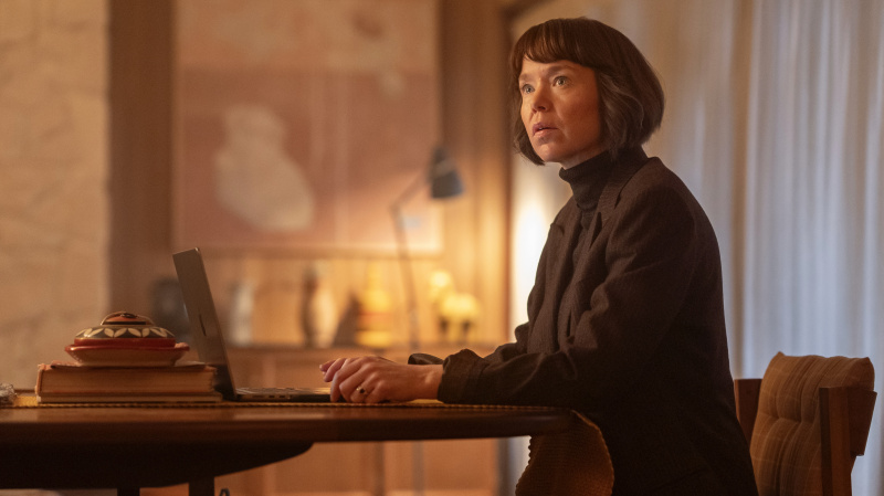   Anna Maxwell Martin tamsiais drabužiais sėdi prie nešiojamojo kompiuterio kaip Lucy Betts-Taylor filme Ludwig.