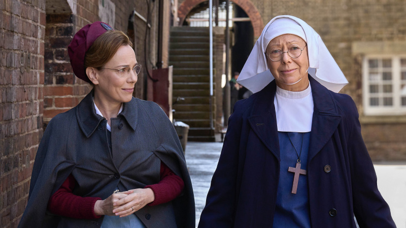   Laura Main sairaanhoitajana's uniform as Shelagh and Jenny Agutter in a habit as Sister Julienne walk along the street in Call the Midwife.