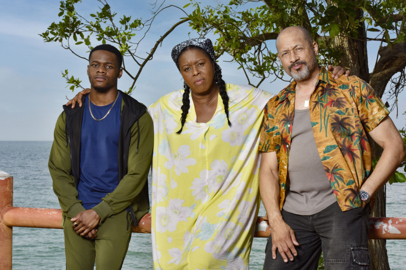   Karlus Brice (Stephen Orubola), Paulette Brice (Michelle Greenidge) ve Damon Clarke (Mark Holden), okyanusa sırtları ile bir veranda üzerinde duruyor. Paulette kolları omuzlarının etrafında ve hepsi kaşlarını çatıyor.