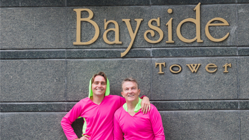   Bradley และ Barney ยืนอยู่หน้าป้าย Bayside Tower ในปานามา