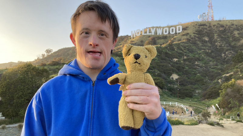   Tommy Goes to Hollywood filmindeki mavi kazaklı Tommy Jessop, oyuncak ayı Roger'ı Hollywood tabelasının önünde tutuyor.