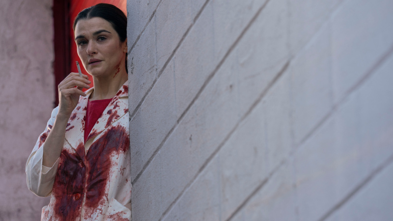  Rachel Weisz en una bata de laboratorio manchada de sangre fumando para Dead Ringers en Prime Video
