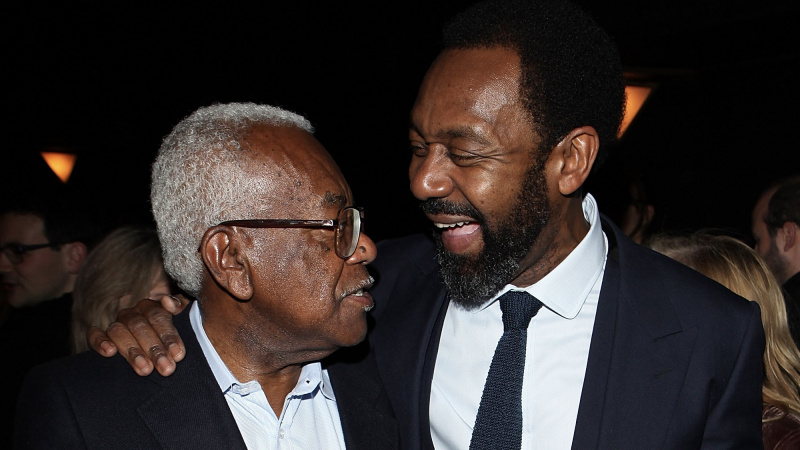   Sir Trevor McDonald a Sir Lenny Henry v tmavých oblekoch zdieľajú vtip na párty.