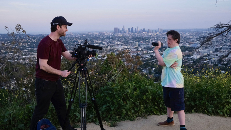   Tommy Jessop Hollywood'a Gidiyor'da kırmızı bluzlu Will Jessop ve mavi bluzlu Tommy Jessop Los Angeles'a bakan bir tepede birbirlerini filme alıyor.