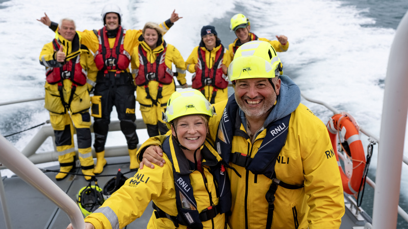   Wynne e Joanna su una barca con l'equipaggio della RNLI, tutti in impermeabili gialli