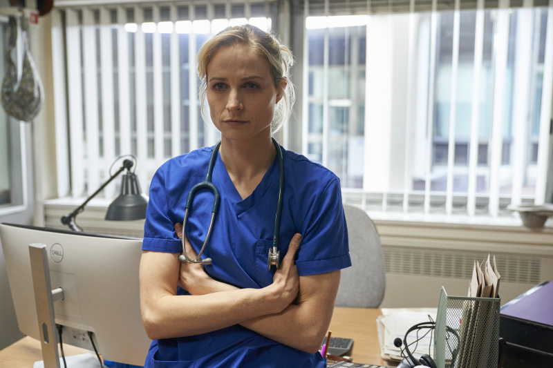   Niamh Algar ในสครับสีน้ำเงินและหูฟังของแพทย์เป็น Dr Lucinda Edwards ใน Malpractice