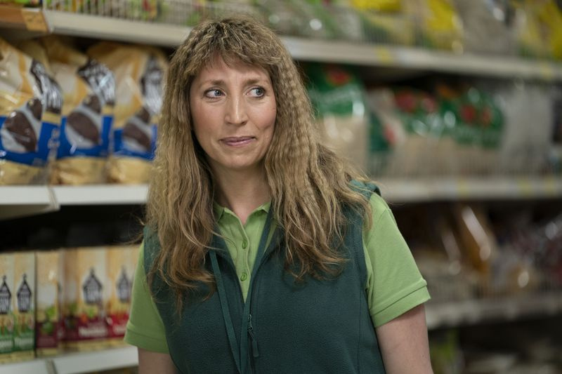 Takaisin elämään: Miri (Daisy Haggard) käyttää vihreää pikeepaitaa ja siihen sopivaa fleece-liiviä koevuorollaan supermarketissa, ja hänellä on myös vastikään poimutetut hiukset.